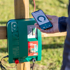 Ein Landwirt kontrolliert das Weidezaungerät Duo Power X6000 smart von AKO mit einer App auf dem Mobiltelephon